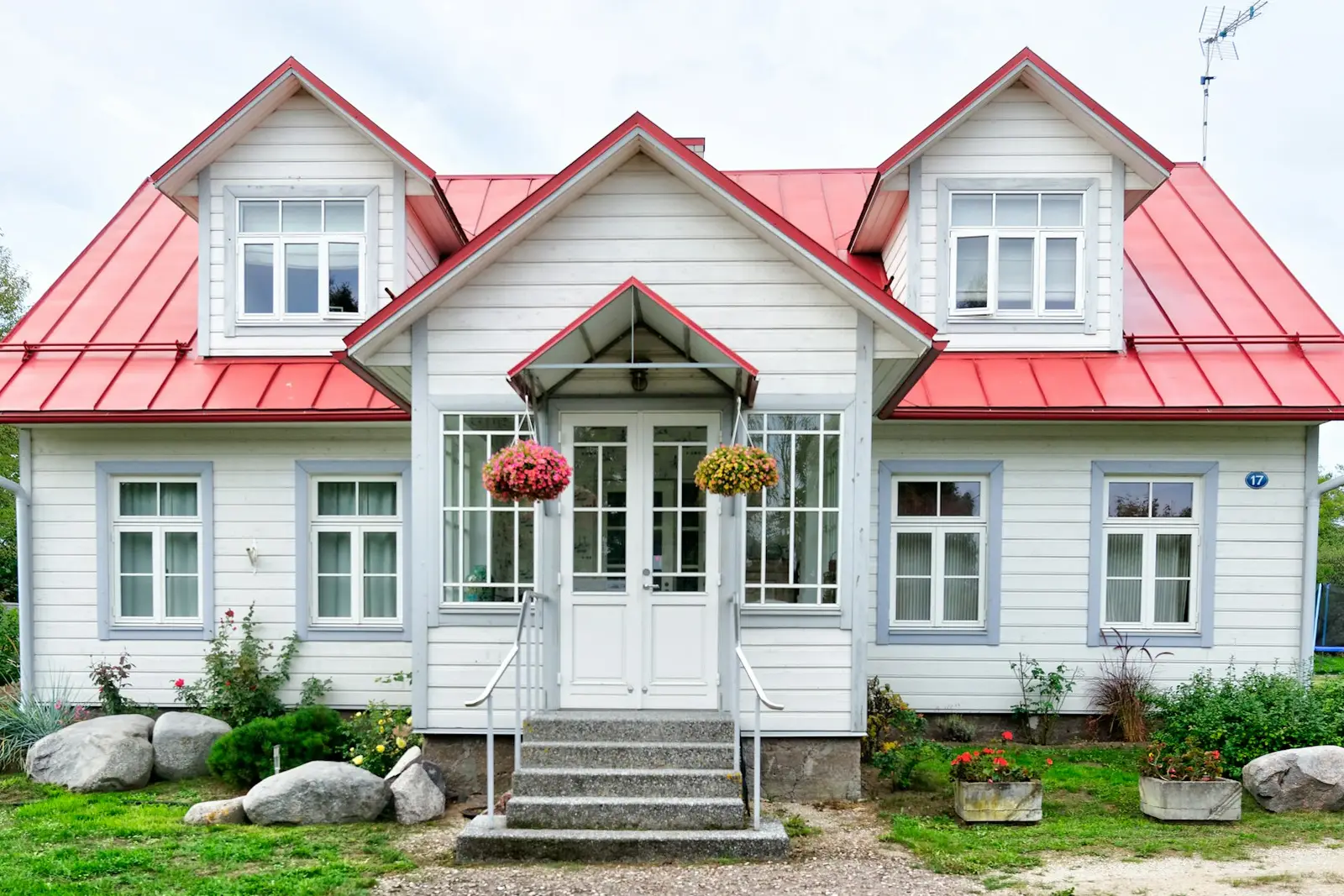 Established older two-story home with a red roof and mature landscaping on a settled street